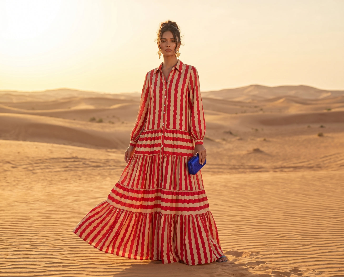 Woman in a red and white striped dress standing in a desert landscape.