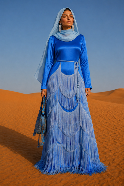 Woman in a blue dress with fringe standing in desert sand