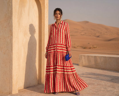 Woman in a red and white striped dress standing in a desert setting with sand dunes in the background.